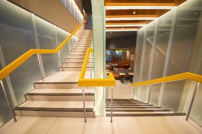 店内半透明的楼梯连接上下两层，梯底以橙色镜面装饰，营造明亮活力的氛围。